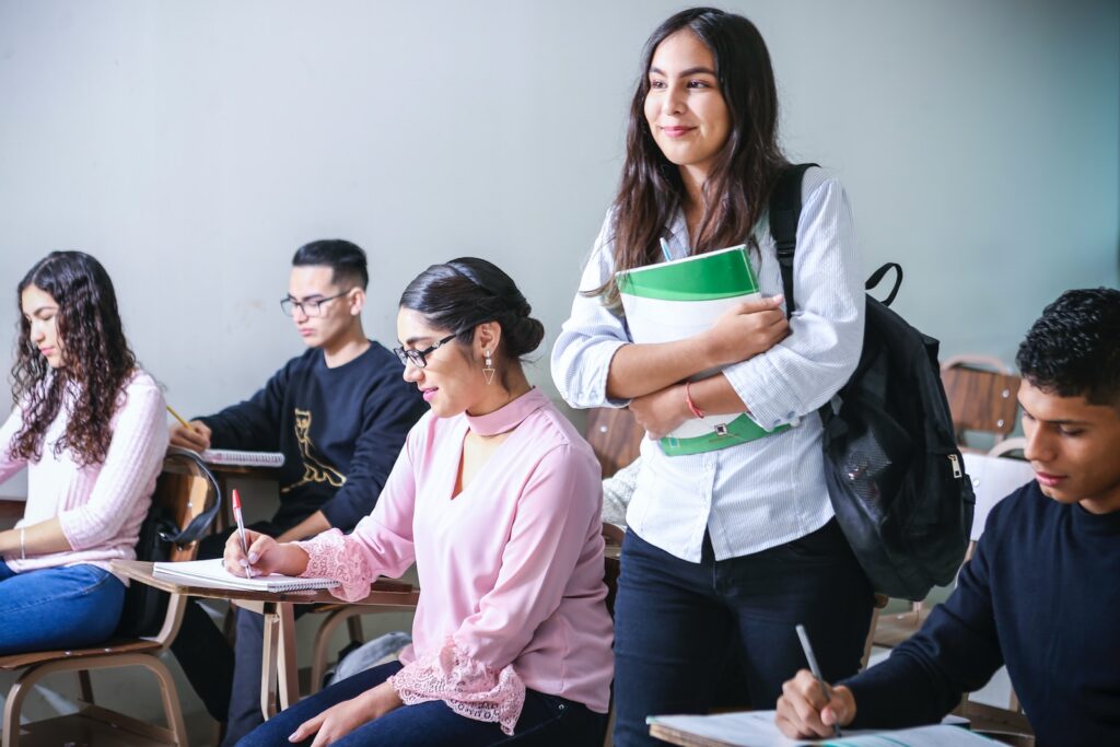 student carrying white and green textbook