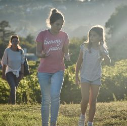 a couple of girls walking across a lush green field