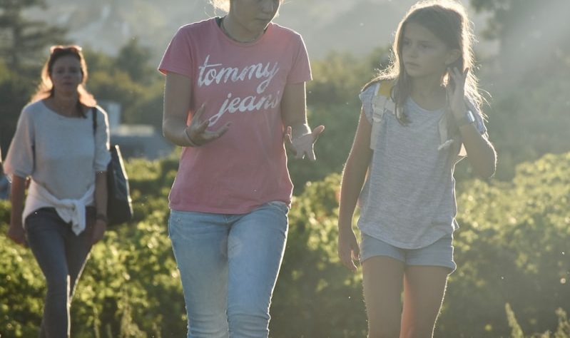 a couple of girls walking across a lush green field