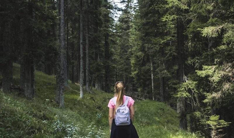 woman carrying backpack on forest