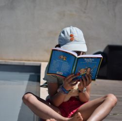 A young child sitting on the ground reading a book in Forsyth County