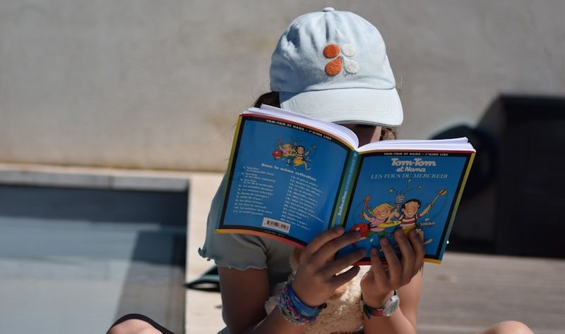 A young child sitting on the ground reading a book in Forsyth County