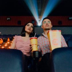 2 people sitting on blue leather chair holding white and red plastic cups