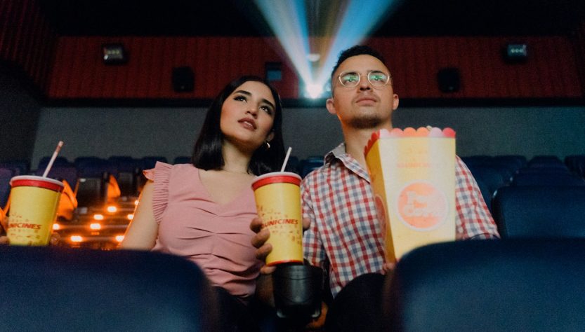 2 people sitting on blue leather chair holding white and red plastic cups