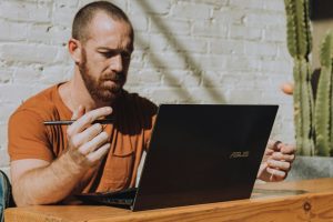 a man sitting at a table using a laptop computer in GA