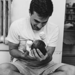 a man sitting on a bed holding a baby