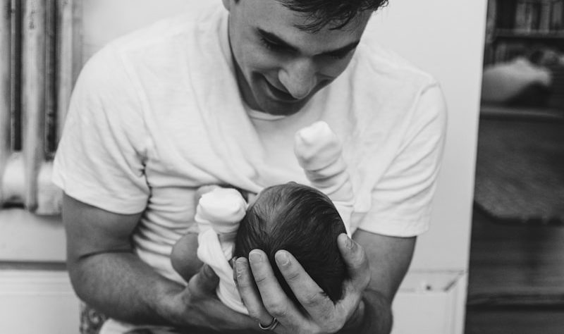 a man sitting on a bed holding a baby