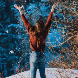woman in brown long sleeve shirt and blue denim jeans standing on snow covered ground