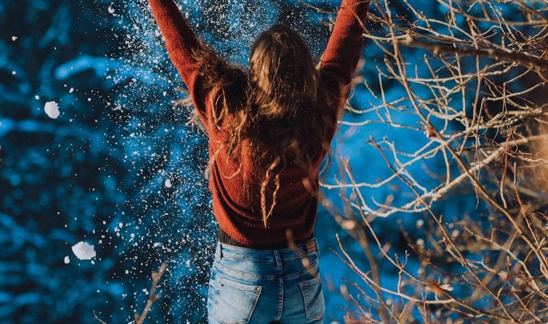 woman in brown long sleeve shirt and blue denim jeans standing on snow covered ground