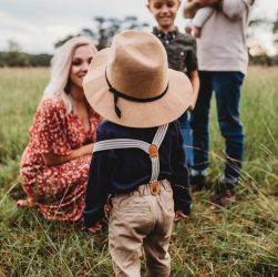 woman sitting on grass in Forsyth County while facing boy in brown hat