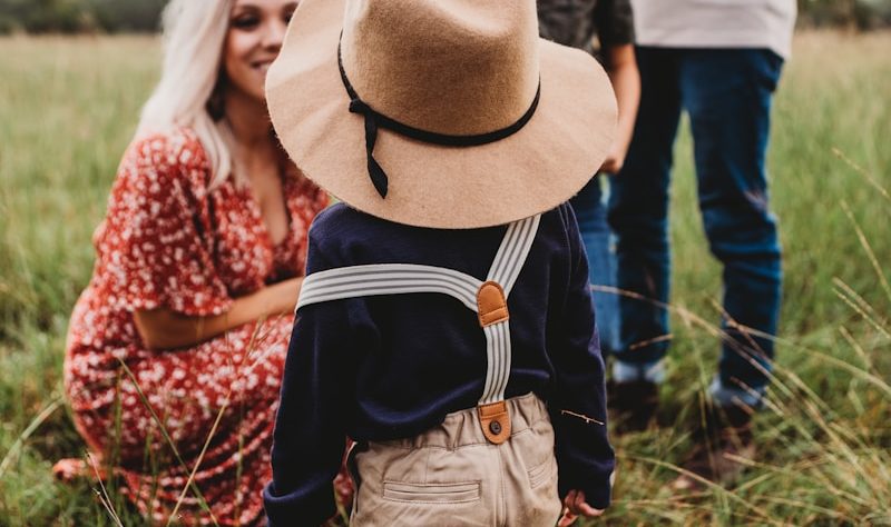 woman sitting on grass in Forsyth County while facing boy in brown hat