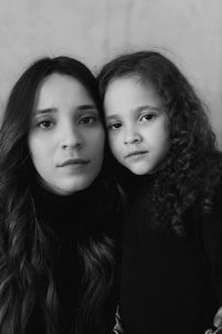Emotive black and white portrait of a mother and daughter with long hair.