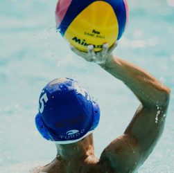 man throwing yellow, blue, and red Mikasa ball