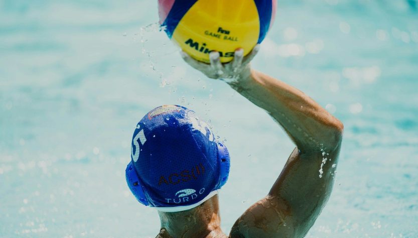 man throwing yellow, blue, and red Mikasa ball