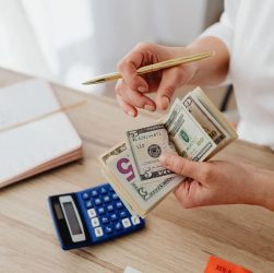 Woman counting money with calculator and receipts on a desk, planning budget.