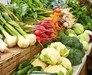 Connie's Cornucopia - organic food straight to your door 2 Fresh vegetables including cauliflower, broccoli, radishes, and onions on a market stall